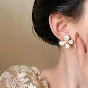 Close-up of elegant 18k gold plated white enamel flower earrings with a pearl center