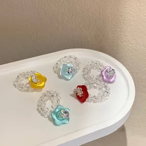 Set of five handmade colorful resin flower button beaded rings on a minimalist white tray