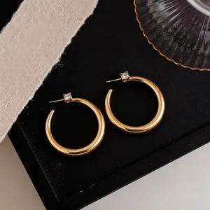 Eleganti orecchini a cerchio placcati in oro 18k con accenti di zircone su vassoio nero