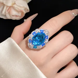 Dettaglio macro di un anello di lusso con gemma blu ovale e castone halo di cristalli