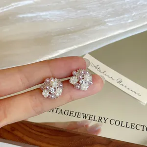 Macro detail of floral stud earrings featuring lavender pearls and sparkling zircons