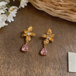 Detailed macro view of 18k gold-plated flower stud earrings with pink teardrop zircon