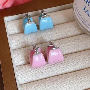 Close-up of pastel pink and blue enamel U-shaped hoop earrings in a cream jewelry box