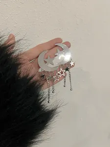 Detailed macro view of silver moon and star tassel earrings held against a textured background