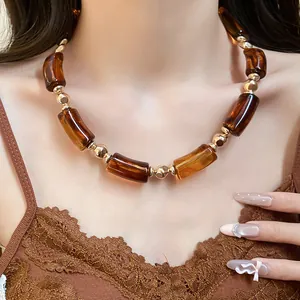 Primo piano di una collana vintage in acrilico ambrato con accenti dorati su modella.
