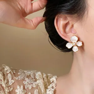 Detailed view of an elegant 18k gold-plated pearl flower earring worn by a model