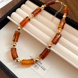 Dettaglio di una collana vintage con perle in acrilico marrone e sfere dorate.