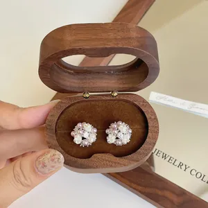 Detailed close-up of zircon and pearl flower stud earrings displayed in a wooden box.