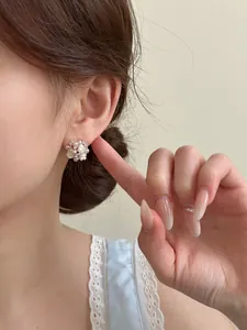 Close-up detail of pearl flower stud earrings worn on ear with zircon accents
