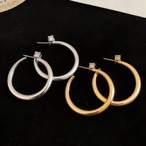 Dettaglio macro di orecchini a cerchio in oro e argento con borchie in zircone quadrato