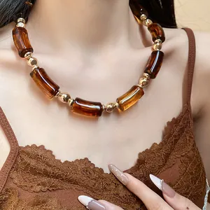 Collana vintage a tubo in acrilico ambra con perle dorate su modella in canotta pizzo