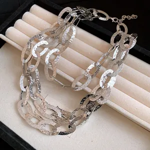 Close-up of triple-layered silver hammered oval link chain necklace in tray