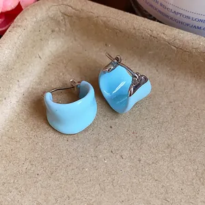 Macro view of light blue U-shaped enamel earrings featuring a minimalist silver-tone clasp.