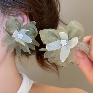 Detailed view of delicate green mesh flower earrings featuring pearl accents on an Asian model