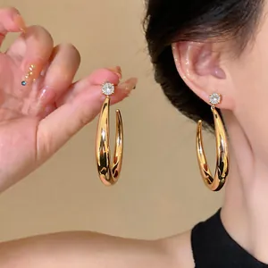 Dettaglio ravvicinato di orecchini rotondi placcati oro 18k con zircone lucido sull'orecchio