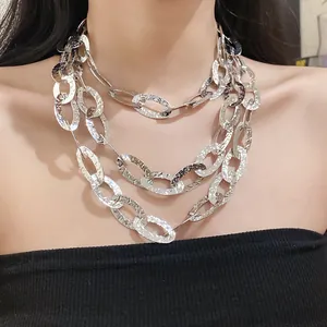 Close-up detail of a layered silver-toned necklace with textured oval links on a model's neck