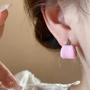Macro close-up detail of stylish pink enamel U-shaped hoop earrings worn on model ear