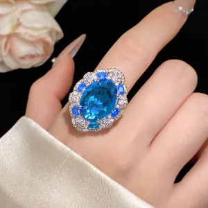 Primo piano di un anello aperto vintage con zircone blu ovale e pavé di pietre al dito