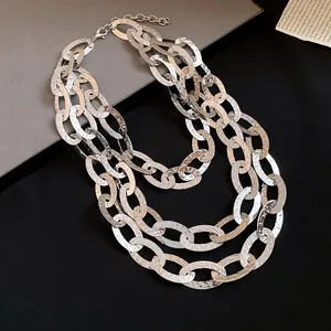 Macro detail of a triple-layer hammered oval chain necklace with silver metallic texture