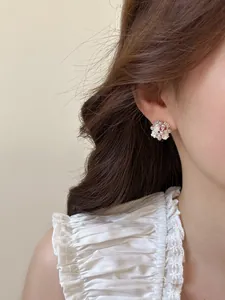 Detail showing elegant white flower stud earrings with pearls and zircons on ear