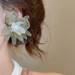 Detailed macro view of green mesh floral earring with central pearl on model's ear