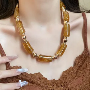 Dettaglio di una collana vintage in perle di acrilico ambra con distanziatori dorati.