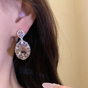 Primo piano di scintillanti orecchini di zircone ovale con pietre halo su modella.