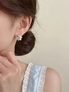 Detailed close-up of elegant floral pearl stud earrings with zircon on Asian model