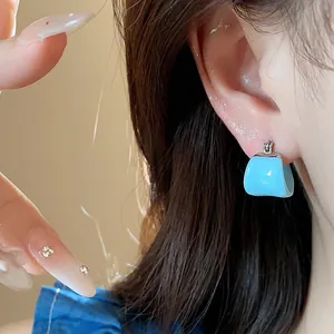 Close-up of elegant sky blue U-shaped drip oil enamel hoop earring on ear