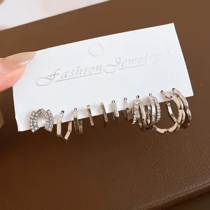 Close-up of a silver geometric earring set with rhinestones displayed on a white card