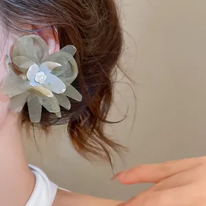 Close-up detail of an elegant green mesh flower earring with a delicate pearl center