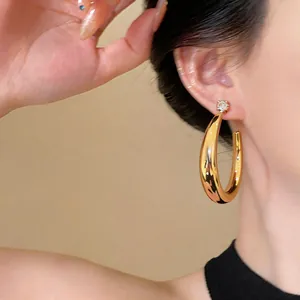Dettaglio di un orecchino a cerchio a C placcato oro 18k con brillante perno in zircone