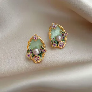 Macro view of exquisite vintage floral enamel earrings with pearl detail and golden frame