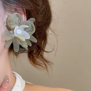 Detailed macro view of green mesh flower stud earrings with a tiny pearl center