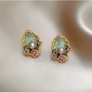 Close-up detail of vintage court style earrings with central pearls and oil painting flower patterns
