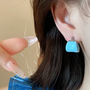 Close-up detail of a minimalist light blue enamel U-shaped hoop earring on ear.