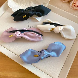 Detailaufnahme von vier Satin-Schleifen-Bananen-Haarklammern in verschiedenen Farben.