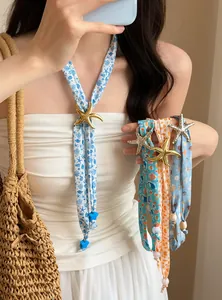 Detail view of seaside style printed fabric necklaces with starfish pendants worn by a model