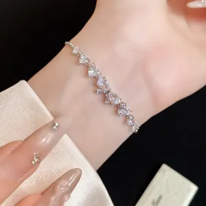 Primo piano di un elegante bracciale regolabile in zircone con cuori e fiocco.