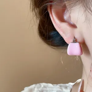 Close-up view of a minimalist pink enamel U-shape hoop earring worn on a model ear.