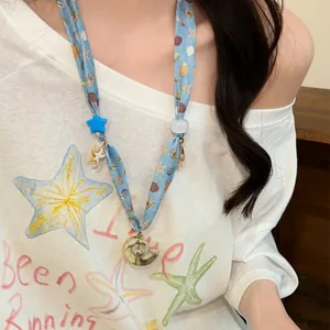 Close-up view of a blue ocean-themed necklace featuring shell and starfish charms.