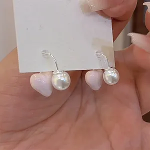 Close-up of pink heart pearl earrings with front-back design and silver tone finish.