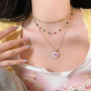 Detail of layered gold necklace with colorful beads and iridescent round pendant