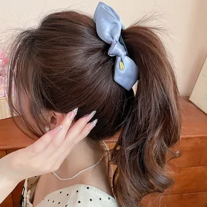 Elegante Nahaufnahme einer blauen Satin-Schleife-Bananenspange für einen Pferdeschwanz
