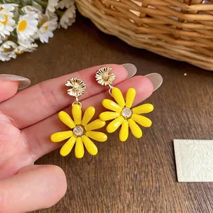 Vibrant yellow daisy stud earrings with sparkling centers for a summer vacation look.