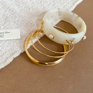 Macro view of a resin bangle with pearl and golden starfish details from the set