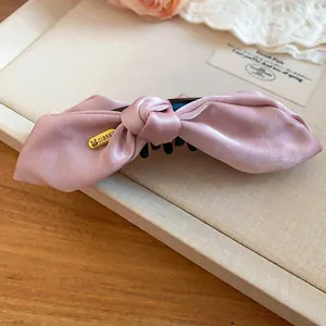 Detailansicht einer rosa Satin-Schleife Bananenspange mit klassischem Goldanhänger