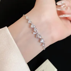 Primo piano di un elegante bracciale in zircone argentato con cuore e fiocco al polso