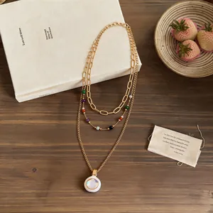 Close-up of a multi-layered gold necklace with colorful stone beads and round pendant
