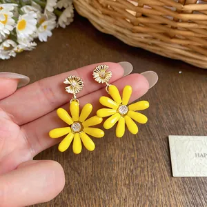 Detailed shot of vibrant yellow daisy earrings with crystal center for summer vacation